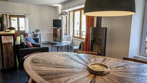 Un soggiorno moderno con un tavolo rotondo in legno, un divano, una televisione e un camino.