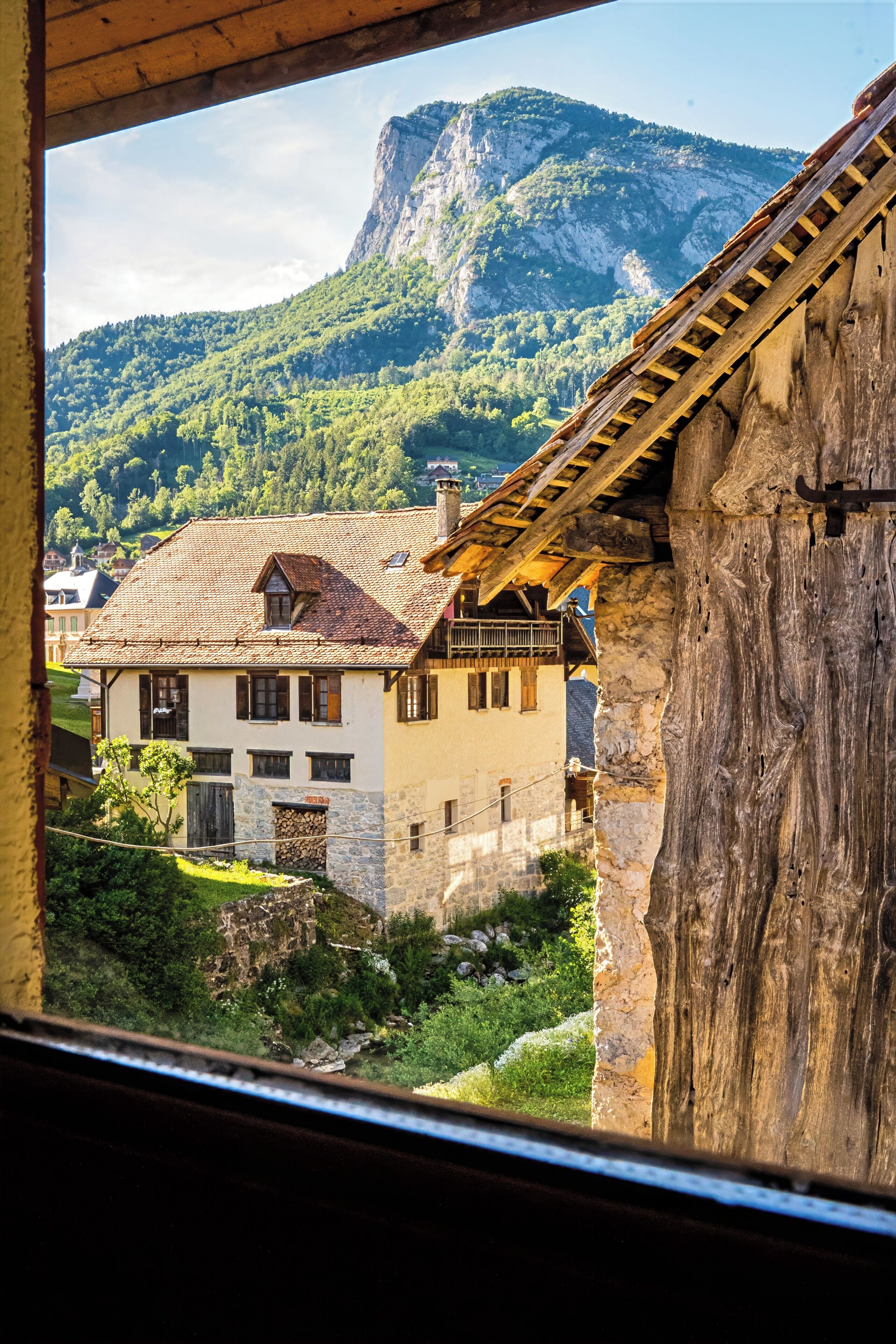 A traditional chalet with a stone facade, wooden beams, and a view of a mountain.