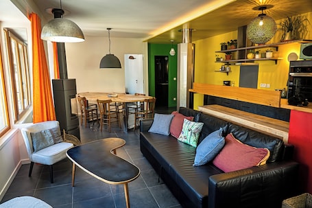 A modern living room with a sofa, chairs, a dining table, and a kitchen area.. Gîte 5 pers Chartreuse: balcony, mountain view, stove, 2 bedrooms, 2 bathrooms | Le Duc