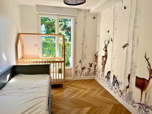 Ein Schlafzimmer mit Bett, Fenster und einer Wand mit Tiermotiven.