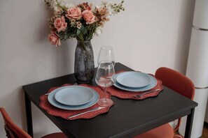 A dining table set with plates, a glass, and a vase with flowers. - Cozy Studio with a Garden | A Place to Work (Wrocław)