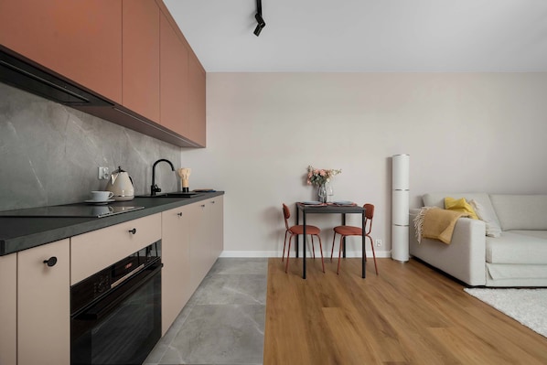 Eine moderne Küche mit schwarzer Arbeitsplatte, Holzschränken und einem Essbereich mit Tisch und Stühlen.