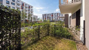 A residential building with balconies, a grassy area, and a fence. - Cozy Studio with a Garden | A Place to Work (Wrocław)