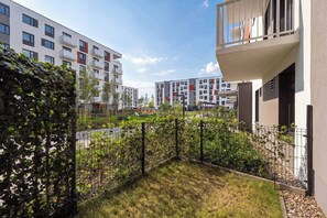 A residential building with balconies, a grassy area, and a fence. - Cozy Studio with a Garden | A Place to Work (Wrocław)