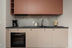 Eine Küche mit Backofen, Kaffeemaschine, Wasserkocher und Spüle.
