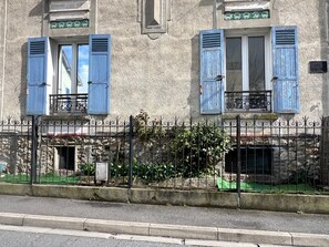 Un edificio con contraventanas azules, fachada de piedra y valla metálica.