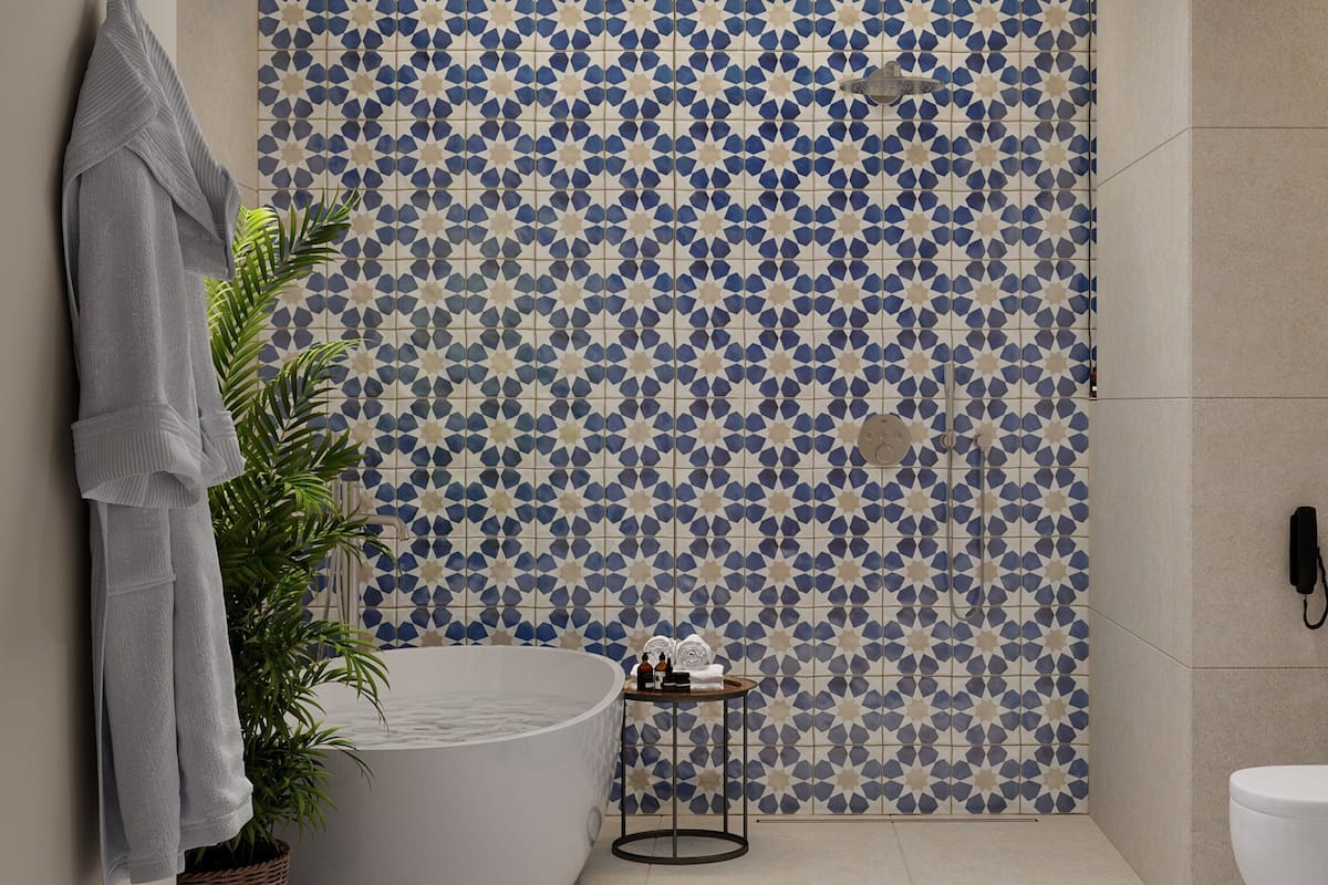 A bathroom with a patterned tile wall, a bathtub, a towel rack, a plant, and a toilet.
