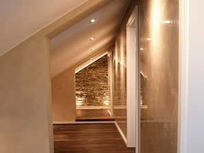 A modern interior with a sloped ceiling, recessed lighting, and a stone wall. - Zimmermann's Lounge 7 - stylish vacation apartment in a central location (Monschau)