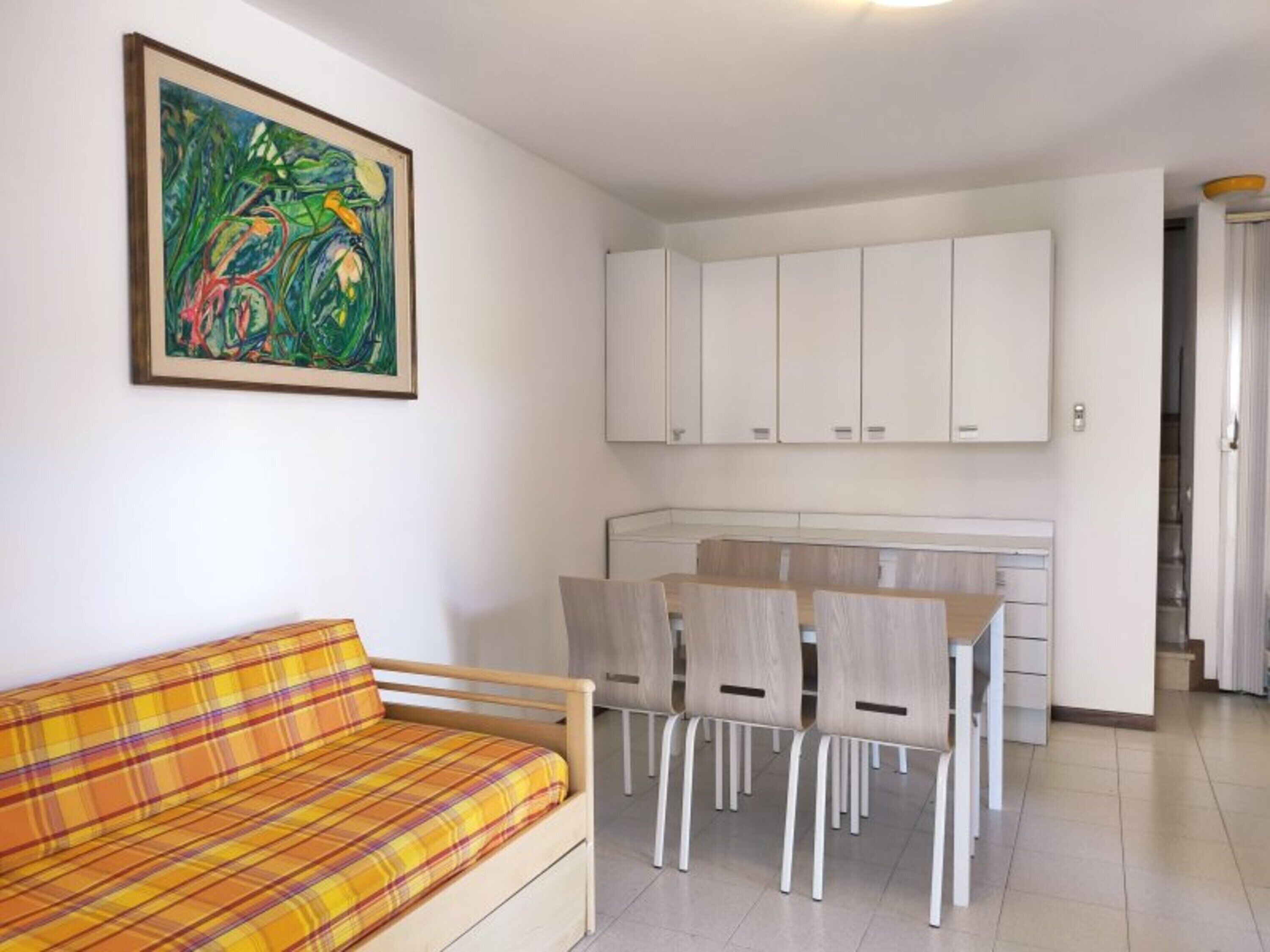 Ein modernes Interieur mit einer Couch, einem Esstisch, Stühlen, Schränken und einem Gemälde.