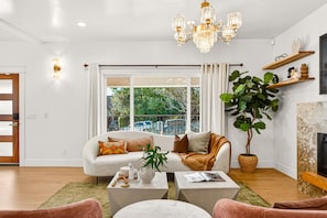 A modern living room with a white sofa, coffee table, and a large potted plant.