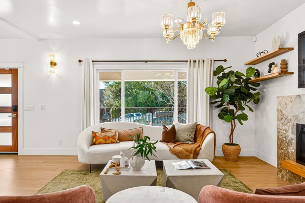 A modern living room with a white sofa, coffee table, and a large potted plant.