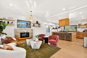A modern living room with a fireplace, a television, and a kitchen area with wooden cabinets.