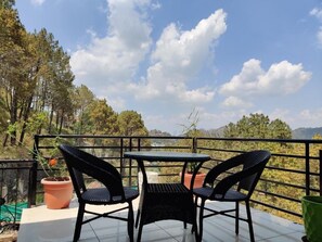 A terrace with two chairs and a table, overlooking a mountainous landscape. - Hotel Heaven and Hills (Kasauli)