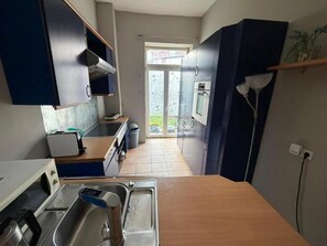 Una cucina compatta con lavello, fornello e pensili.