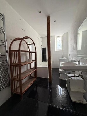 A bathroom with a wooden shelf, a bathtub, a sink, and a mirror. - Kaiserslautern · Entire Building · 13 Rooms · Sleeps 25 (Kaiserslautern)
