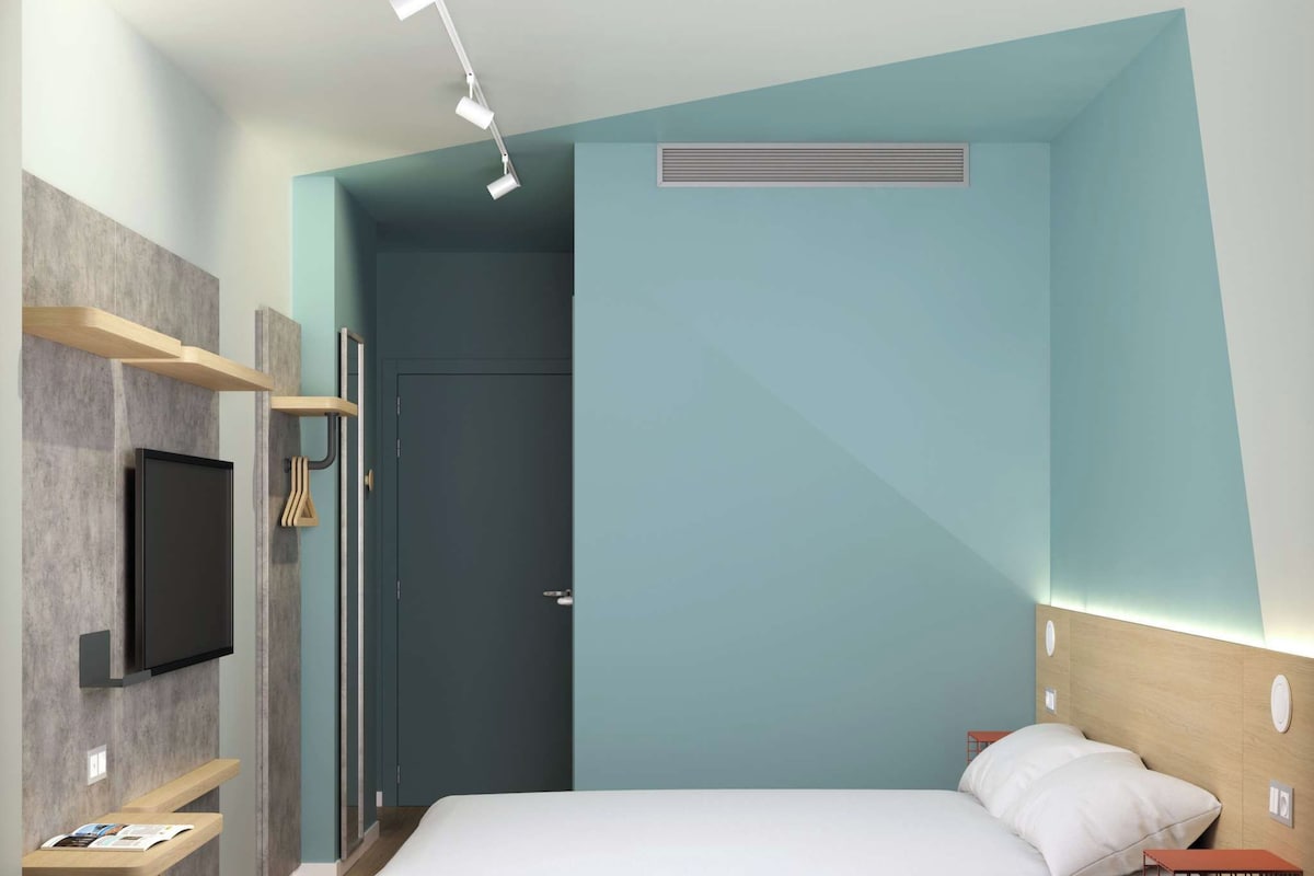 A modern bedroom with a bed, a TV mounted on the wall, and a built-in shelf.