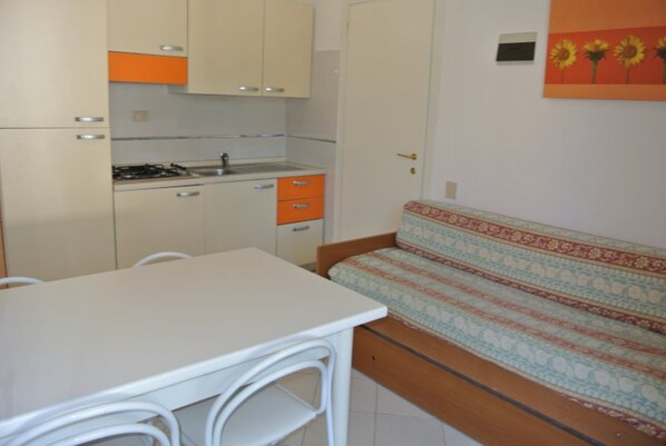 Une cuisine compacte avec une table et un canapé, un petit meuble et une porte dotée d’une poignée.