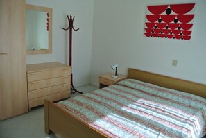 Une chambre à coucher avec un lit en bois, une table de chevet, un miroir, un porte-manteau et un élément décoratif mural.