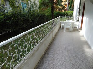 Ein Balkon mit weißer Reling, einem kleinen Tisch und Stühlen.