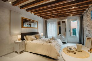 Une chambre à coucher avec un lit, une table de chevet, une lampe et une vue sur l’extérieur.