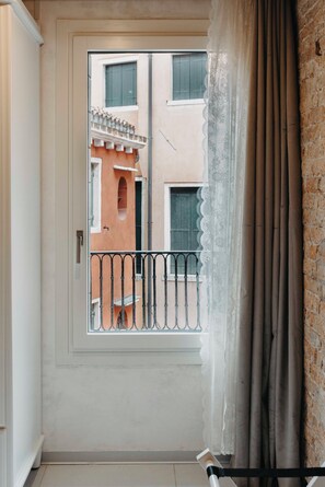 A room with a window, a balcony with a metal railing, and a curtain. - Dimora Quadri | 1 min from St. Mark's Square | Romantic Retreat for Couples (Venezia)
