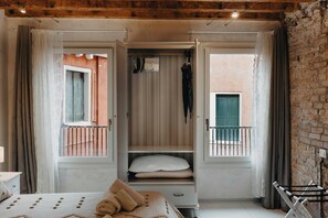 Une chambre avec un lit, une armoire, un balcon et un mur en briques.