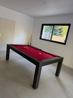 A pool table with balls, a window with a view of greenery, and a door. - Villa escape and spa (Limoges)