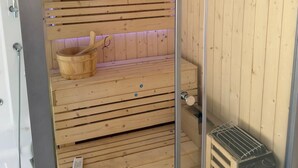 Una sauna de madera con bancos, un balde de madera y un calentador.