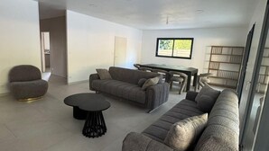Un salón espacioso con un sofá modular, una mesa de centro redonda y un comedor con mesa y sillas.