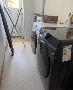 A laundry area with a front-loading washing machine, a drying rack, and a box on the counter. - Villa escape and spa (Limoges)