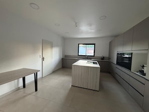 A modern kitchen with a central island, a window, and a door. - Villa escape and spa (Limoges)