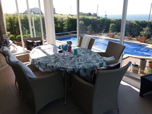 A patio with wicker furniture, a table with a tropical print tablecloth, and a view of a swimming pool and greenery. - Villa Bellerose direct seaview, 4 bedrooms, private heated pool - golf - beaches (Bozhurets)