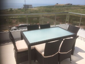 A balcony with a glass table and wicker chairs, overlooking a grassy area and buildings. - Villa Bellerose direct seaview, 4 bedrooms, private heated pool - golf - beaches (Bozhurets)