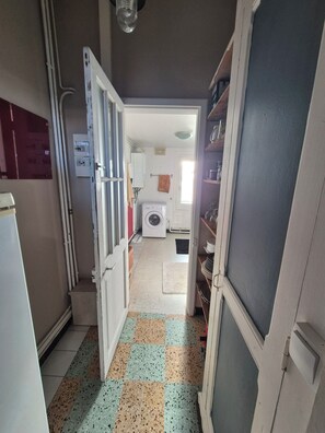 A narrow hallway with a tiled floor, leading to a laundry area with a washing machine and a dryer. - Fourasine family home 300m from the beach (Fouras)