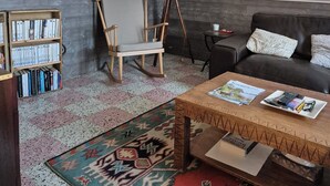 A living room with a bookshelf, a rocking chair, a coffee table with magazines, a floor lamp, and a couch. - Fourasine family home 300m from the beach (Fouras)