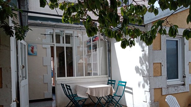 A patio with a table and chairs, a window with bars, and a door. - Fourasine family home 300m from the beach (Fouras)