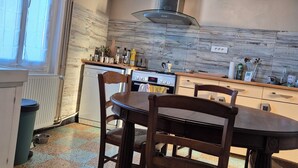 A kitchen with a dining table, chairs, a stove, and a window. - Fourasine family home 300m from the beach (Fouras)