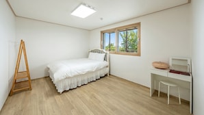 Un dormitorio con cama, escritorio, silla, escalera y ventana.