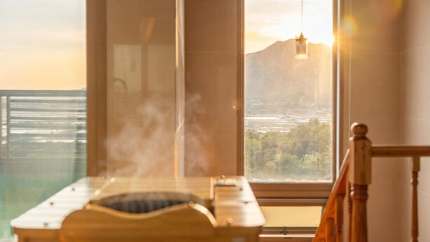 Una habitación con sauna, un ventanal con vistas al paisaje y una lámpara colgante.