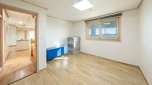 A room with a wooden floor, a blue cabinet, a window with a view, and a door leading to another room. - Ganghwa Sunset Hill Private Pension (Incheon)
