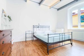 Une chambre à coucher avec un lit en métal, une commode en bois et une fenêtre donnant sur un paysage agréable.