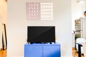 A modern room with a flat-screen TV on a blue cabinet, wall art, and a refrigerator. - Discover Persio Sky, a fully renovated apartment with a modern design, created to offer a comfortable and relaxing stay in the heart of La Spezia. Located on the top floor of a building with an elevator, it provides a bright and peaceful atmosphere, perf (La Spezia)