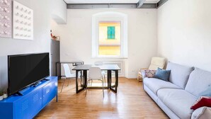 Un salon moderne avec un téléviseur à écran plat, une table à manger et un canapé.