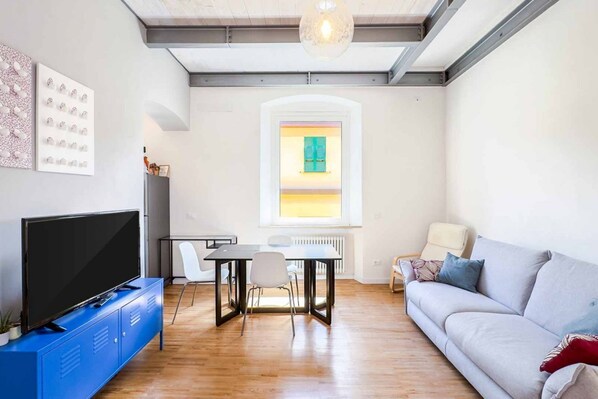 Een moderne woonkamer met een flatscreen televisie, een eettafel en een bank.