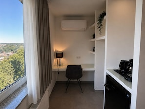 A modern room with a desk, chair, air conditioning unit, and a coffee machine. - Elion Hotel Siegen (Siegen)