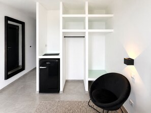 Une cuisine moderne avec des meubles blancs, un lave-vaisselle noir et une chaise noire.