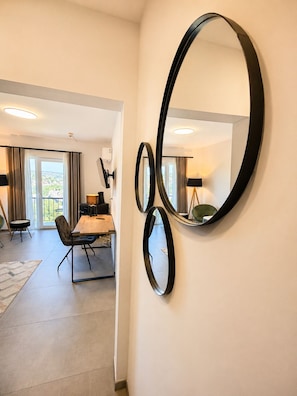 A modern hotel room with a dining area, a large mirror, and a view of the city. - Elion Hotel Siegen (Siegen)