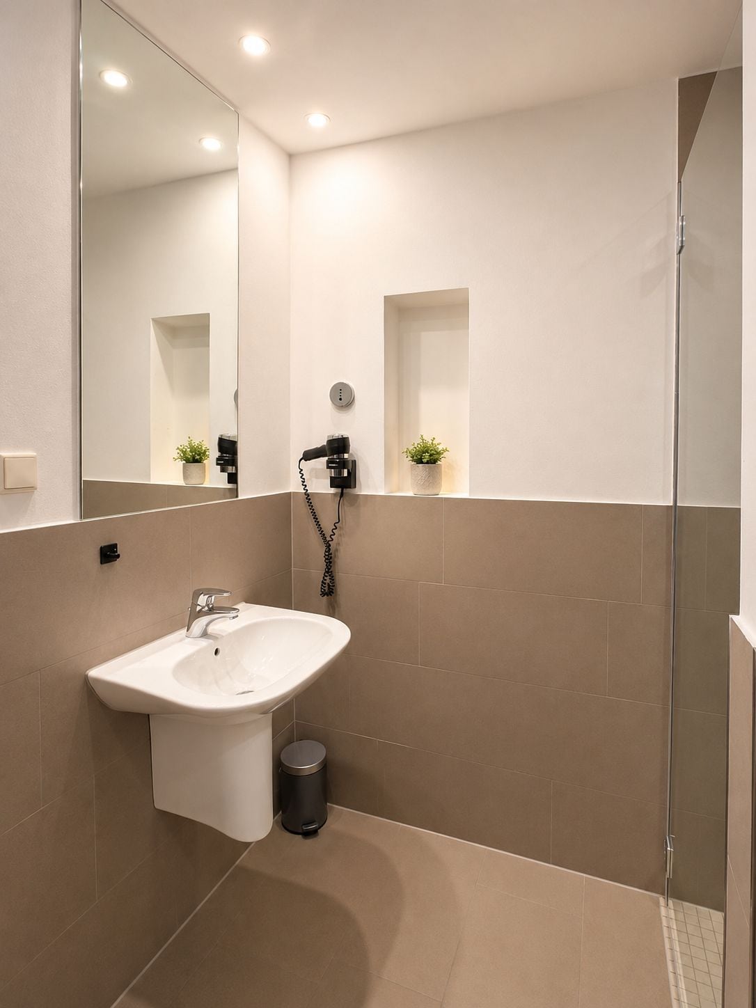 Un baño moderno con lavabo, espejo y ducha.
