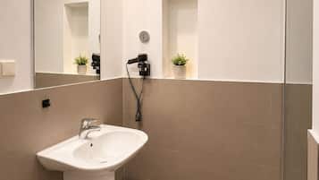 Un baño moderno con lavabo, espejo y ducha.