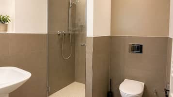 Un baño moderno con ducha, inodoro y lavamanos.